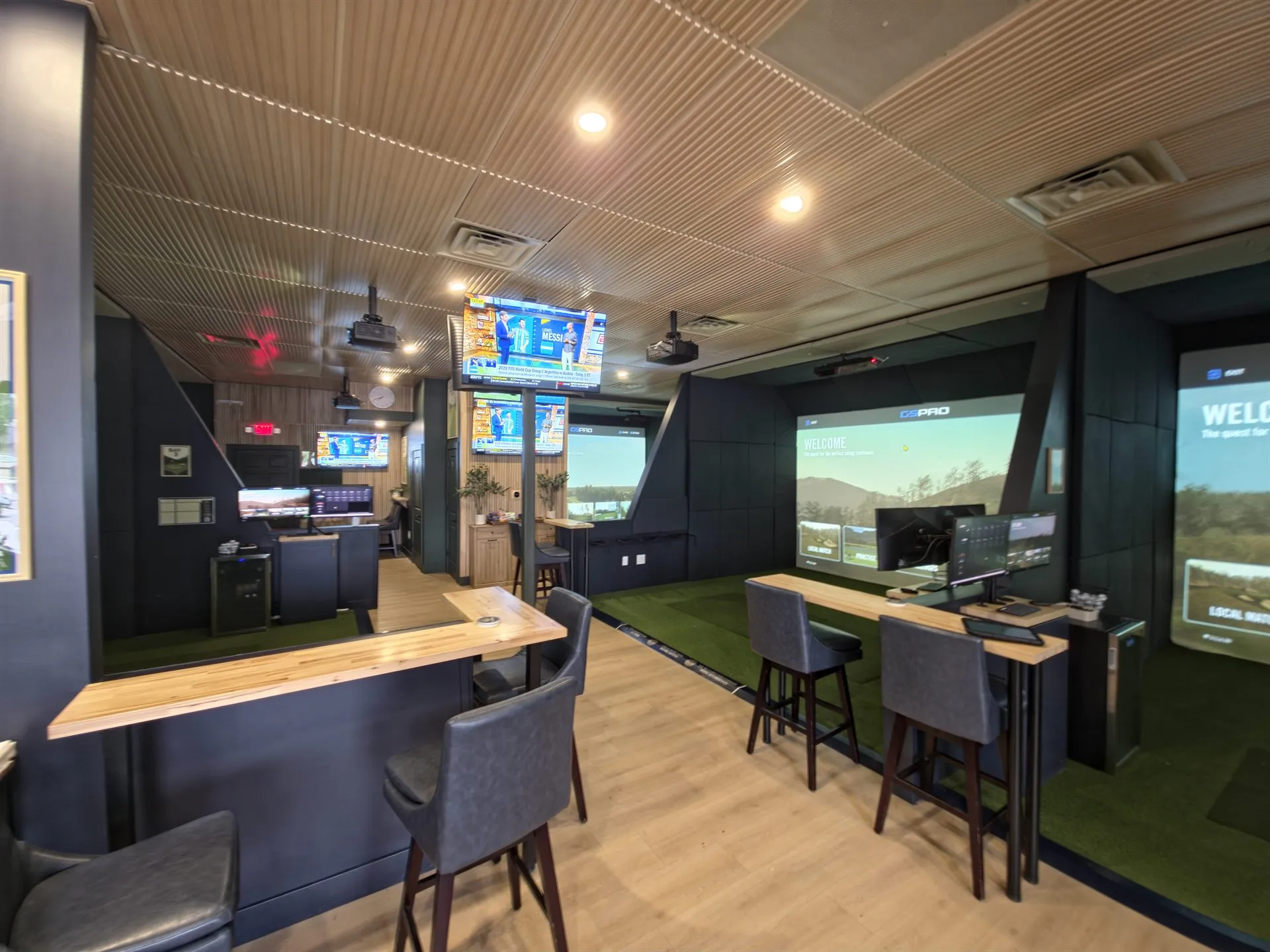 Interior of All Seasons Indoor Golf Club in Kansas City with multiple golf simulator bays, bar-height seating, and sports TVs